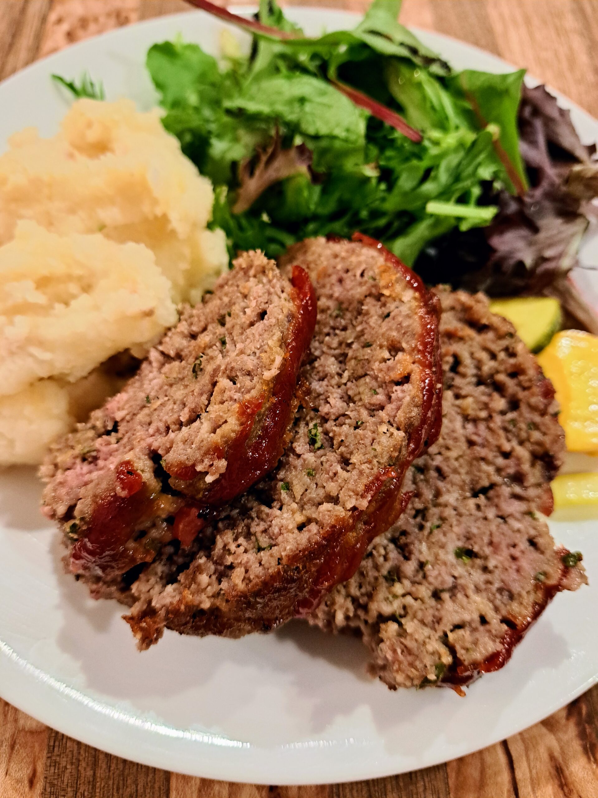 sliced meatloaf with mashed potatoes and greens